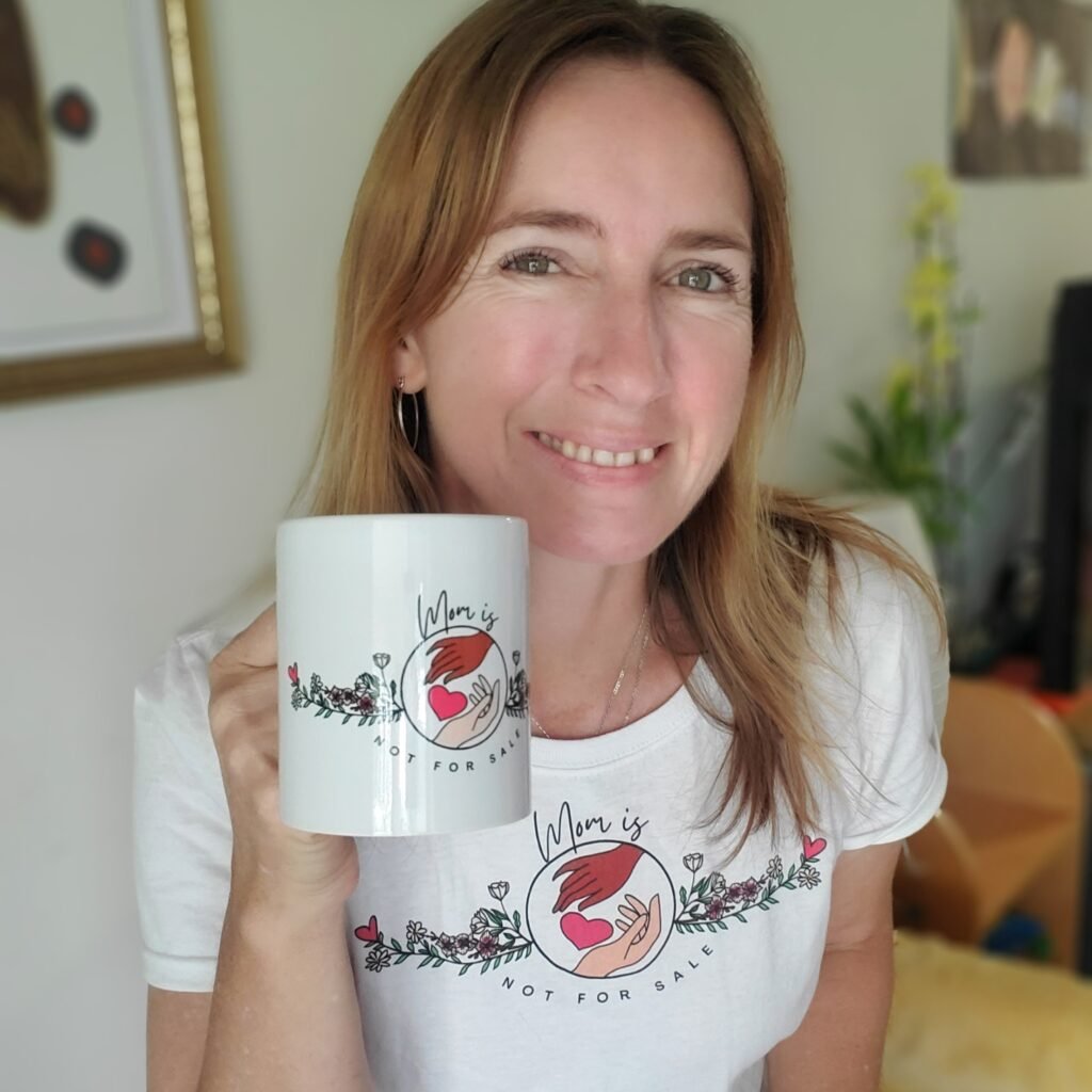 Simone wearing the official Mom Is Not For Sale logo t-shirt and holding a cup with the Mom Is Not For Sale official logo on it.